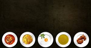 schwarzes Bild mit 5 verschiedenen Speisen auf Tellern unten