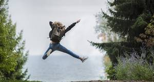 Frau im Wald springt in die Luft