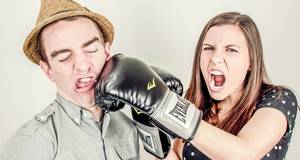 Junge Frau schlägt Mann mit Boxhandschuh