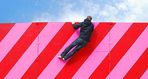 Mann hängt an pink-rot gestreifter Wand