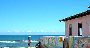 Frau am Strand, kleine Mauer, Meer und Strandhaus
