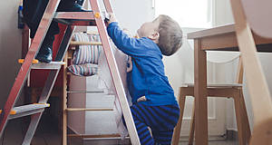 Kleinkind auf Leiter im Wohnzimmer