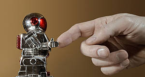 Menschenhand berührt kleinen Roboter