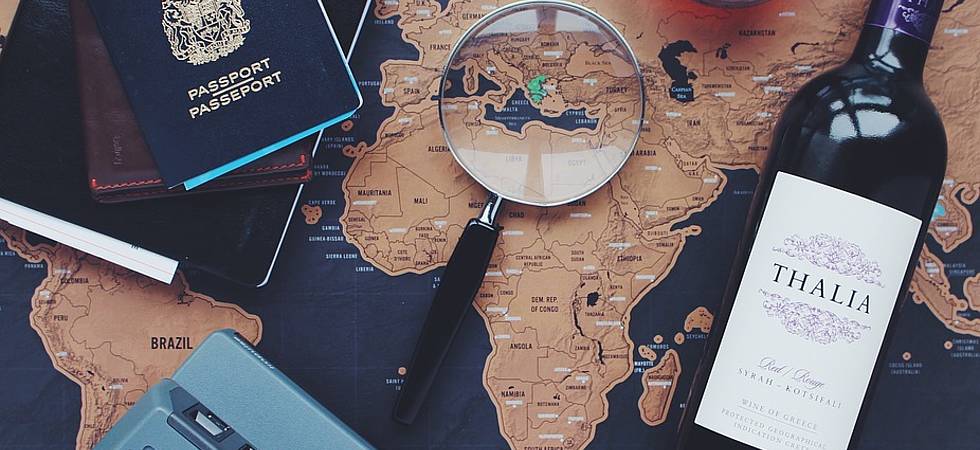 Reisepass, Wein, Lupe liegen auf Weltkarte