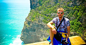 Mann sitzt vor Felswand auf Bali