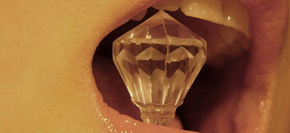 Nahaufnahme Mund einer Frau mit Kristall zwischen den Zähnen