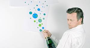 Mann mit Flasche Sekt in der Hand und an der Wand grüne und blaue Punkte die Sekttropfen darstellen sollen
