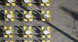 gelbe Stühle mit Tischen aufgereiht
