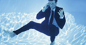 Mann telefoniert im Pool unter Wasser