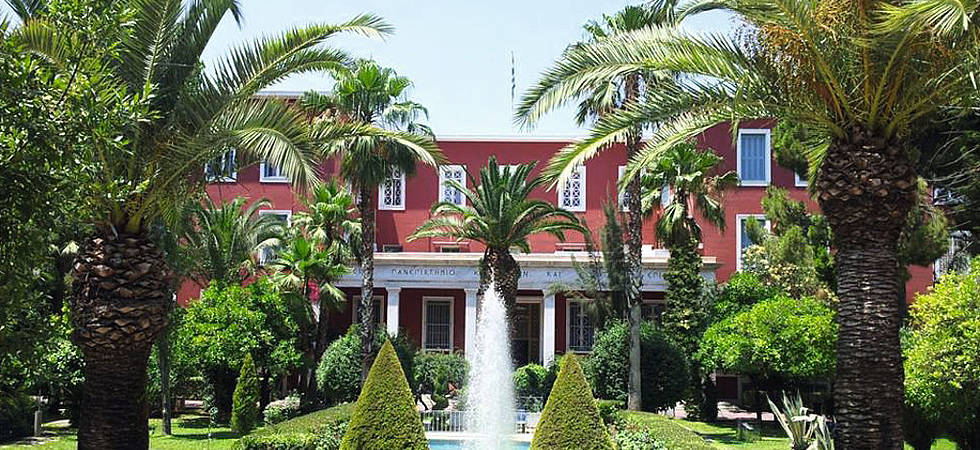 rotes Haus hinter Palmen und Springbrunnen