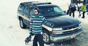 Junge mit Snowboard im Schnee vor SUV