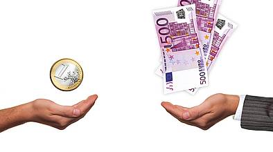 Zwei aufgehaltene Hände, über einen en Euro, ander mehrere 500 Euroscheine