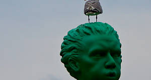 grüner Tonkopf eines Mannes mit Möve auf dem Kopf