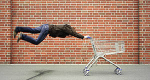Mann hängt senkrecht an Einkaufswagen