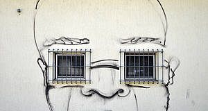 gemaltes Gesicht an der Wand mit Gittern vor den Augen