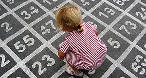 Kind sitzt auf großem Zahlenfeld