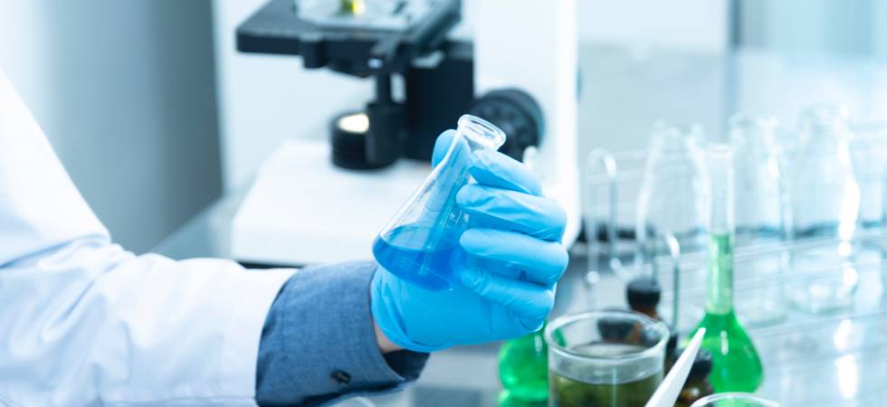 Labor, Mensch in Kittel und blauen Handschuhen hält Reagenzglas mit blauer Flüssigkeit in Hand