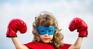 Kleines Mädchen verkleidet als Superheld mit roten Boxhandschuhen