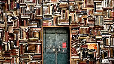 Bücher kreuz und quer rund um eine alte Tür gestapelt