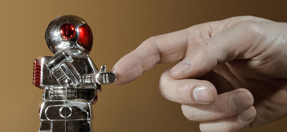 Menschenhand berührt kleinen Roboter
