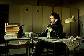 Frau sitzt am Arbeitsplatz und telefoniert