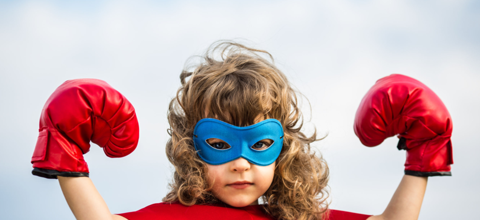 Kleines Mädchen verkleidet als Superheld mit roten Boxhandschuhen