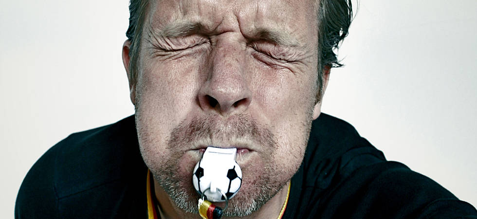 Mann, der angestrengt in Fußball-Deutschland-Pfeife trillert