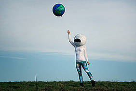 Frau mit Weltraumhelm hängt an Weltkugelballon