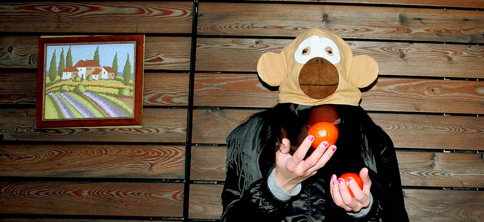 Mann mit Affenmaske jongliert Äpfel