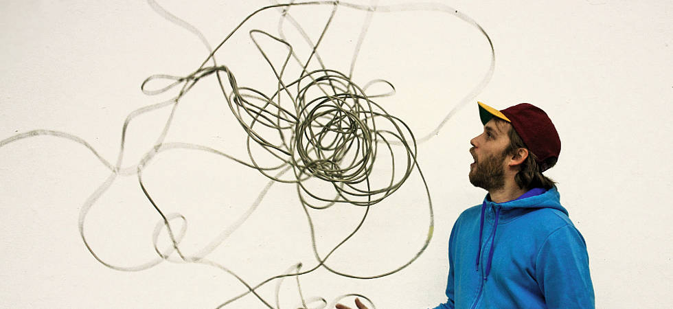 Mann mit Cap wirft langes Netzkabel in die Luft