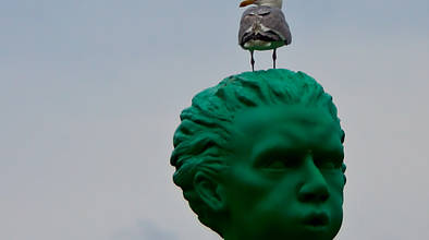 grüner Tonkopf eines Mannes mit Möve auf dem Kopf